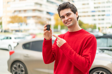 Young handsome man with car key and pointing it