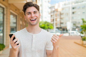 Young handsome man using mobile phone while doing thumbs up