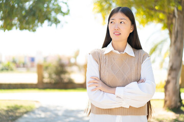 Pretty Chinese woman at outdoors with confuse face expression