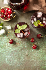 Cold refreshing cherry cola in a glass with ice on a stone background, summer juice. View from above. Copy space.