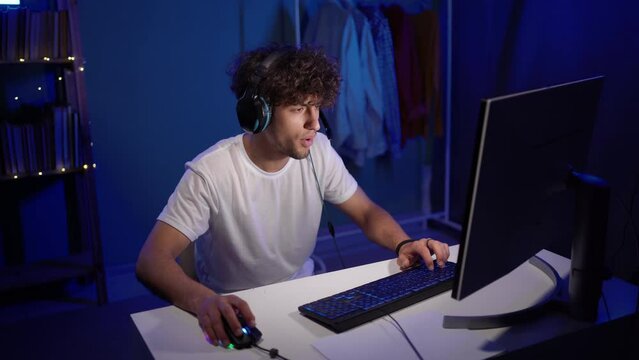 Gaming at home. Happy Arabic gamer winning a round in online video game on his computer. Muslim guy enjoying online multiplayer championship.