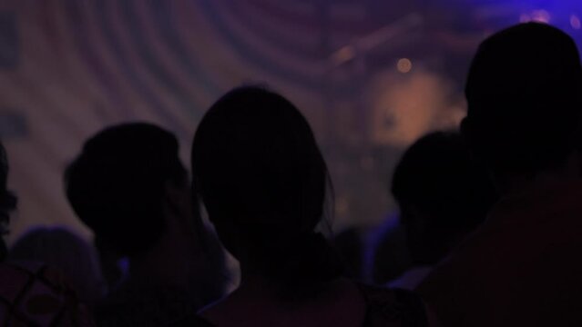 Silhouette of people dancing at a concert in the dark slow motion. People dancing and jumping at disco. Evening enjoyment in music club. Nightlife, modern music and entertainment concept