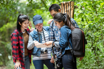 Group asian friends traveler with backpack adventure holding map to find directions and walking relax in the jungle forest outdoor for destination leisure explore education nature on vacation