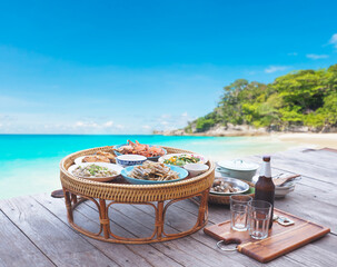 Thai seafood set served on bamboo tray on wooden floor over summer beach background - 621476206