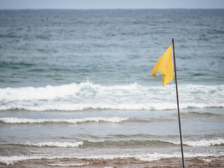yellow flag on the beach. Bathing up to the waist