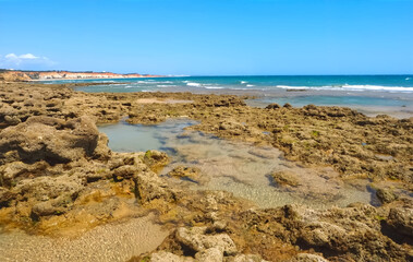 typical Algarve beach with red cliffs Praia Maria Luisa in Portugal