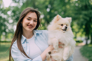 Portrait of a young woman with her dog. Pomeranian in the hands of his owner.