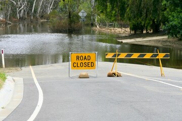 Road blocked by the Flooded Murray River with Road Closed sign and barrier on the Victorian and New...
