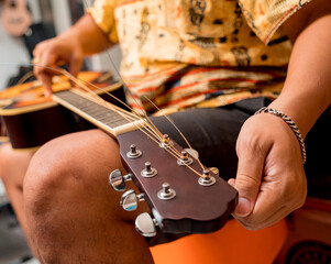 Young musician changing strings on a classical guitar in a guitar shop