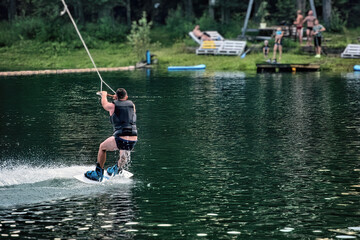 A man wakeboarding on a lake on summer day in a life  jacket. Soft focus. Action blur.