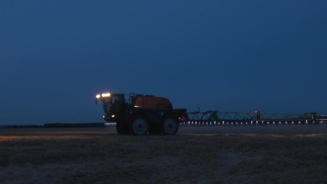 This stock video shows agricultural machinery at night for processing agricultural crops with fungicides, mineral fertilizers. This video will adorn your projects related to agriculture, agronomy, pes