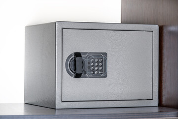 grey closed safe for storing money and documents with buttons on the shelf of the wardrobe in the...