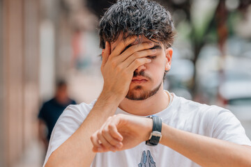 student or young man in the street desperate looking at the clock