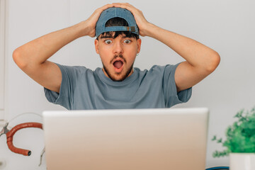 student or young man at desk shocked looking at computer