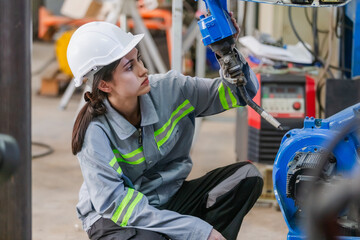 Engineers woman checking condition robotic arm. female technician industrial checking robotic arm machine. engineering machine maintenance check up robot.
