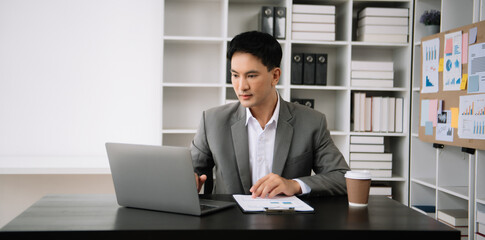 Fototapeta premium Confident Asian man with a smile standing holding notepad and tablet at the modern office.