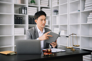 Naklejka premium Asian man lawyer reading legal book with gavel on table in office. justice and law ,attorney concept.