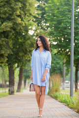 business woman in a blue long shirt is walking down the alley in the city