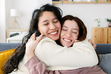 Close up front view of happy young millennial girls women friends hugging each other at home....