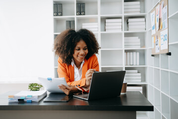 Successful African Businesswoman Analyzing Finance on Tablet and Laptop at modern Office Desk tax, report, accounting, statistics, and analytical research concept..