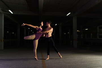Fototapeta na wymiar Talented couple of dancers doing a ballet dance in dark street