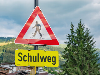 people crossing sign on a road by a school in German language