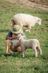 A happy moment of a male farmer feeding his sheep.
