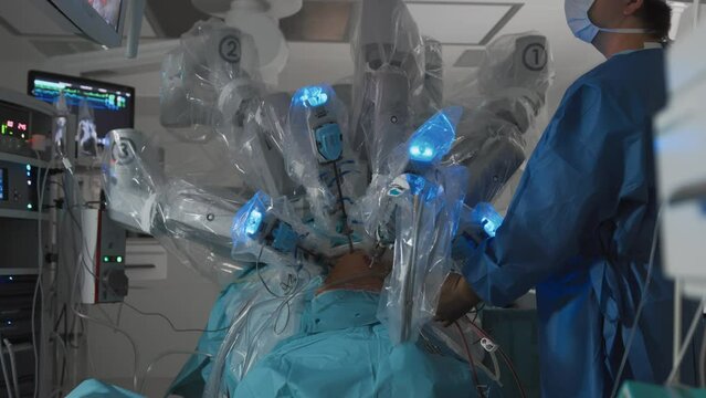 Unrecognizable doctor controls process of automatically performing surgery in patient's abdomen using medical robot. Modern medical technology and scientific innovations