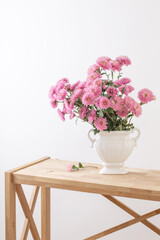 pink chrysanthemums in white vase on white interior