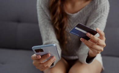 Close up of woman hands holding credit card and smartphone. Young woman paying online using banking entering data shopping order in internet store secure payment.