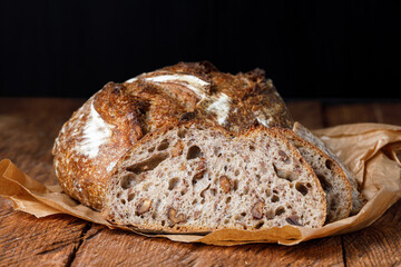 Traditional sourdough bread with nuts sliced on a rustic wooden background, close up. 