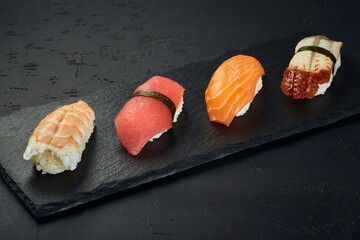 Nigiri Sushi with shrimp, salmon, tuna and eel on dark background. Sushi menu. Japanese food.