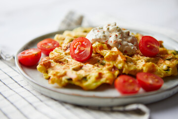 Snack waffles with bacon, cheddar cheese, spinach, sauce and cherry tomatoes on light background