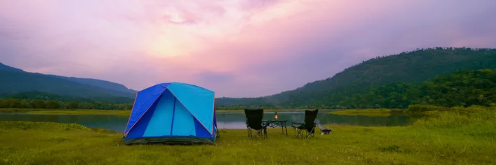 Fotobehang Camping Tent Near the Natural Lake and Mountain View with Outdoor Gear, Rustic Lantern on Table and Camping Chairs, Babeque grill in Evening Time. Panoramic View. © KL 1981