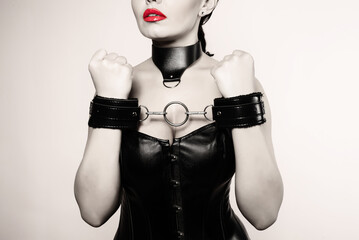 Submissive girl in leather black corset, handcuffs and collar waiting for punishment