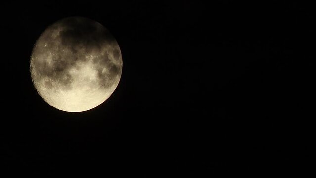 Black clouds fly by in front of the full moon against the background of a black night sky