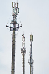 Telecommunication towers on the background of a cloudy sky. Vertical photo