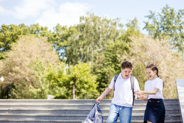 Two teenagers, a boy and a girl, friends, go to school, laugh merrily. Back to School. Copy space