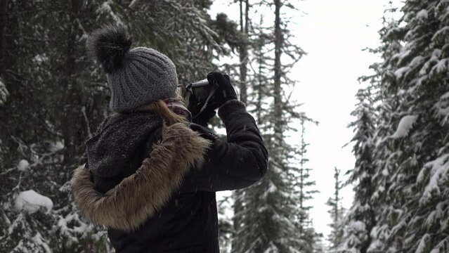 Girl taking digital photos in snow with camera 4k