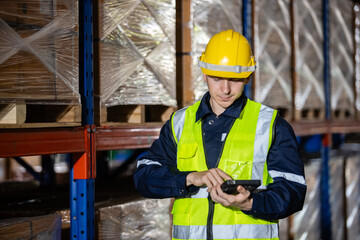 Naklejka na ściany i meble Male professional worker wearing safety uniform and hard hat using digital tablet inspect product on shelves in warehouse. Man worker check stock inspecting in storage logistic factory.
