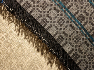 Latvian traditional hand-woven wool blanket corner with fringes on linen tablecloth background