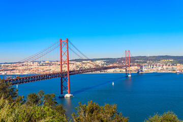 Naklejka premium The 25th April Bridge (Ponte 25 de Abril) is a suspension bridge road-rail over the Tagus river that connects the city of Lisbon to the city of Almada. View from Almada.