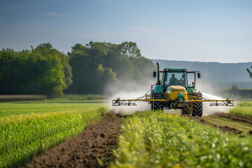 Fototapeta premium Tractor spraying pesticides on soybean field with sprayer at spring, background