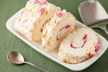Homemade Meringue Cake Sweets Roll with Raspberry jam on ceramic plate.
