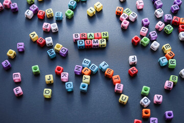 The word BRAIN DUMP on colorful mini cubes with scattered cubes on the black background