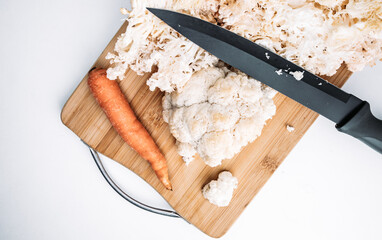 Hericium erinaceus or Lions mane mushroom with a knife and carrot.