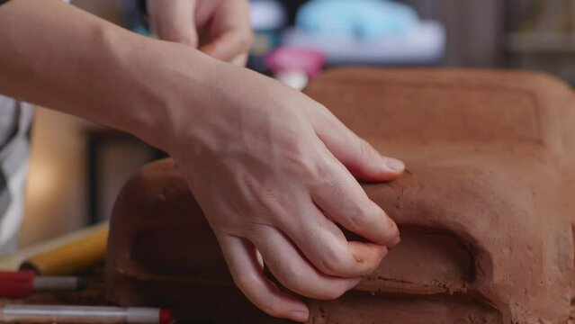 Close Up Of Man Automotive Designer'S Hands Smooth Out The Surface And Create Details In The Sculpture Of Car Clay In The Studio
