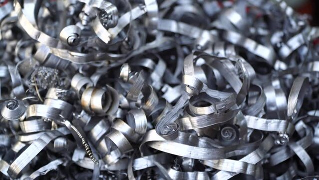 Steel scrap materials recycling. Aluminum chip waste after machining metal parts on a cnc lathe. Closeup twisted spiral steel shavings. Small roughness sharpness,