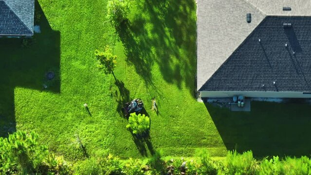 Aerial view of man worker cutting grass in summer with a professional lawn mover vehicle
