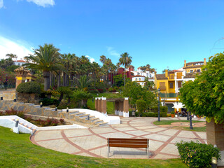 Fototapeta premium beautiful park and central square with palm trees in La Alcaidesa with nice colorful houses, Cádiz, Andalusia, Malaga, Spain